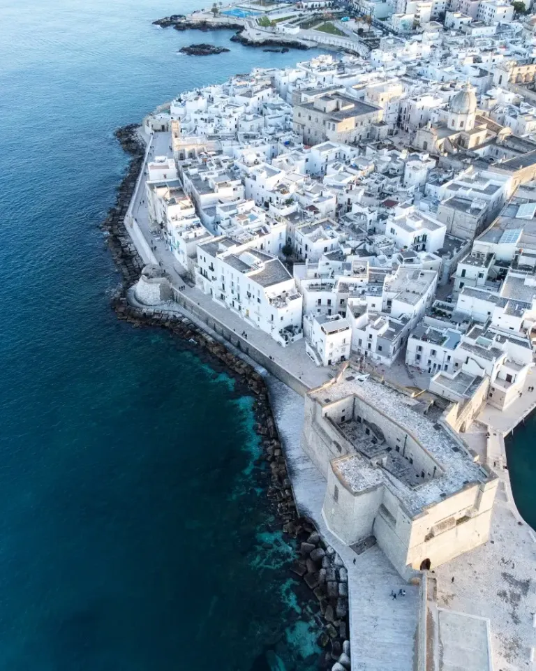 Vista aerea di un centro storico costiero in Puglia con mare cristallino